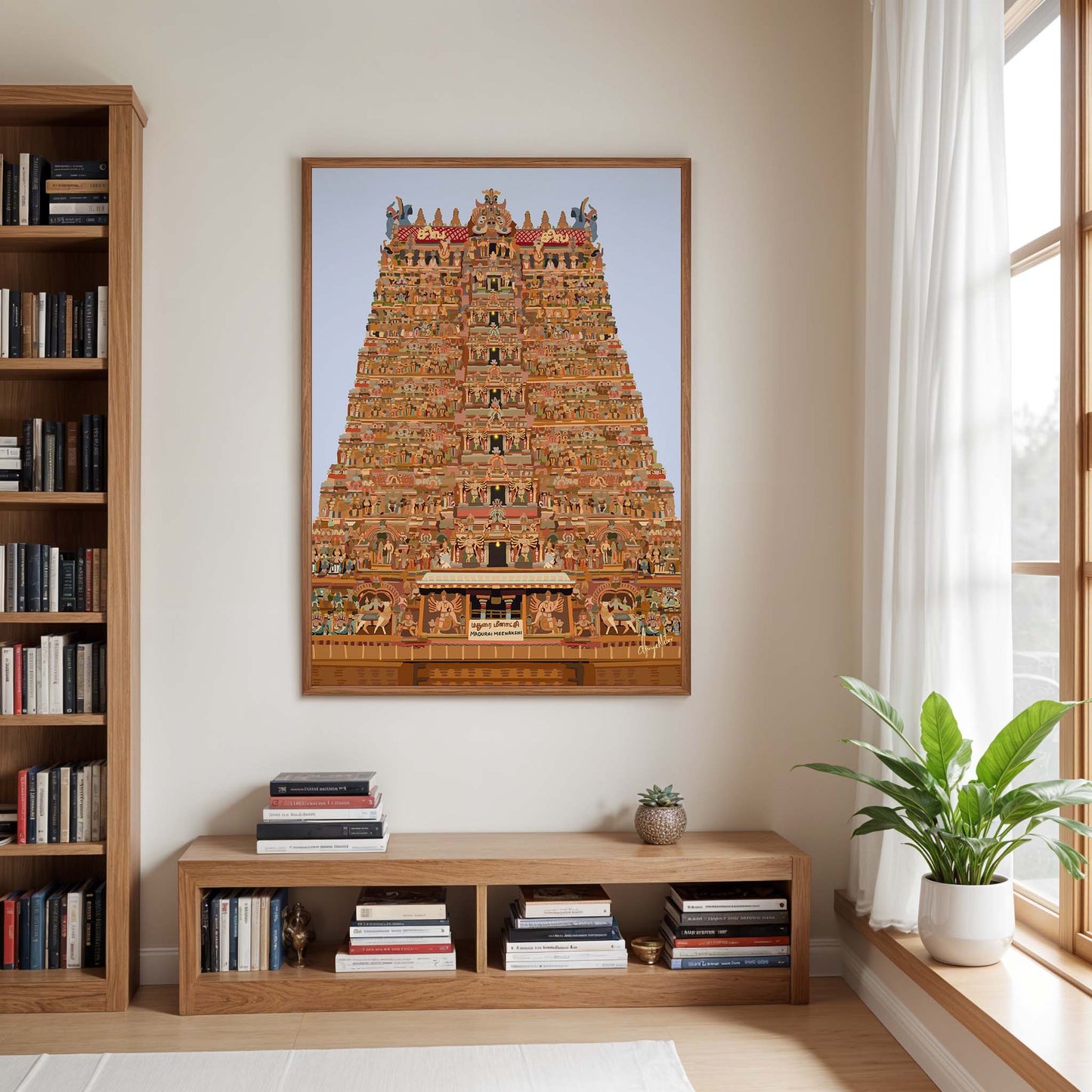 Framed artwork of a temple on a wall in a room with books and a plant.