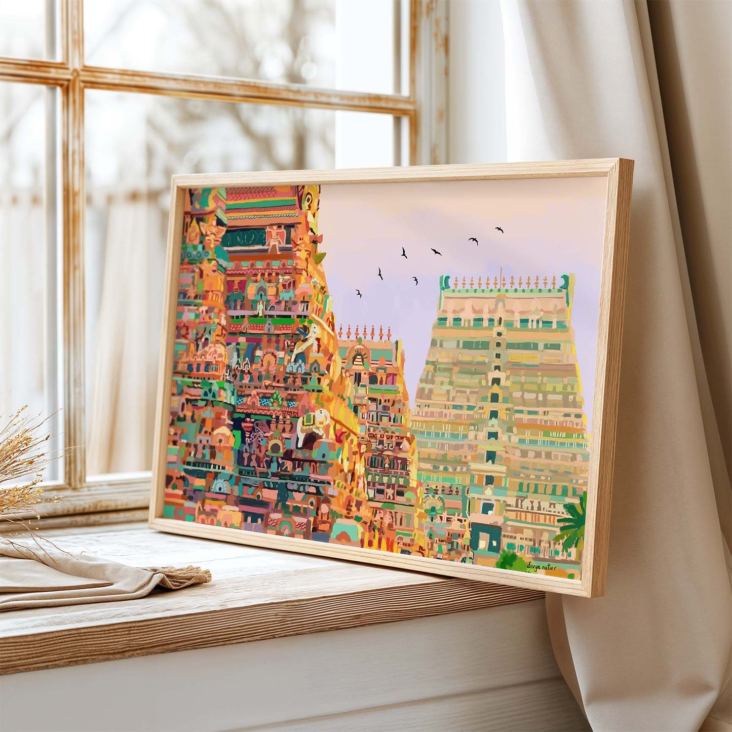 Framed colorful artwork of a temple on a windowsill with natural light.