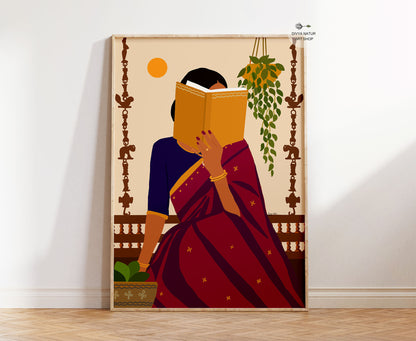 A framed art print leaning against a white wall on a light wood floor. The print features a stylized illustration of a woman in a deep red and navy blue sari, holding a yellow book to her face, with a hanging green plant and a yellow sun in the background.