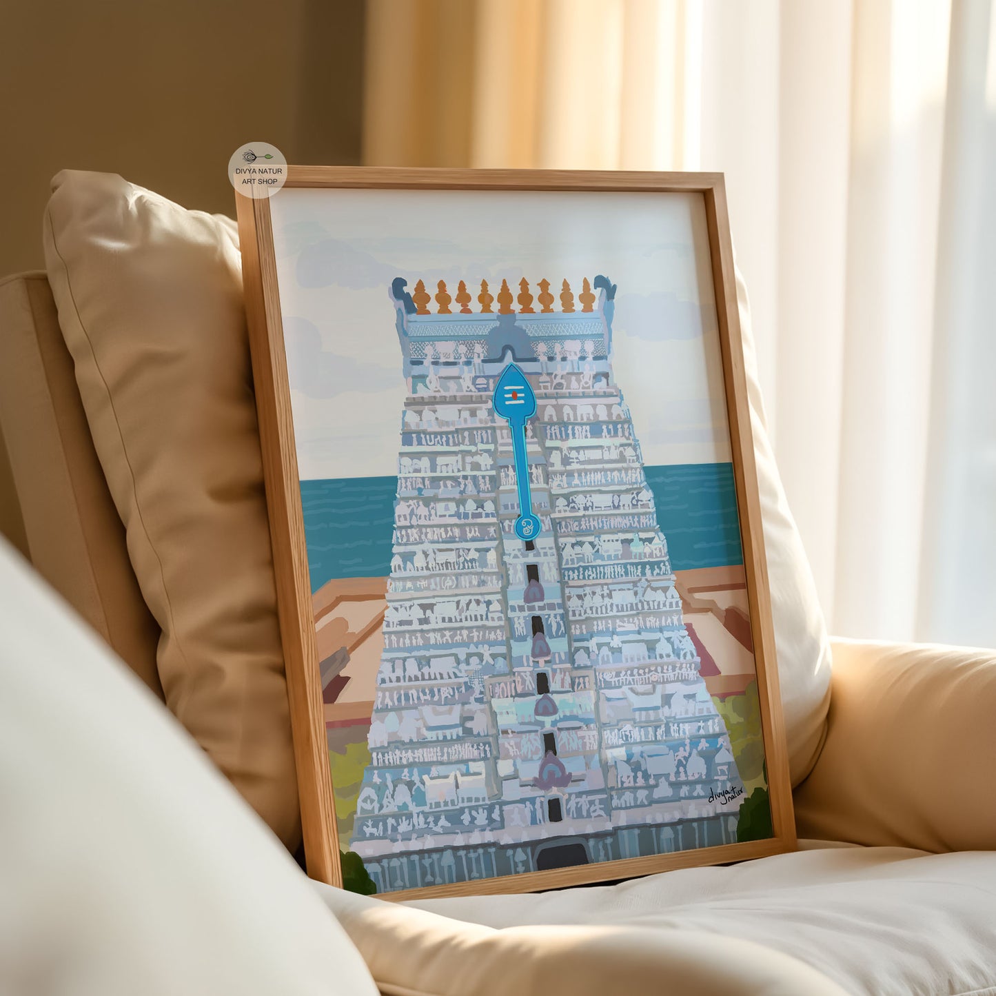 Framed artwork of a Tiruchendur temple tower  on a beige couch.