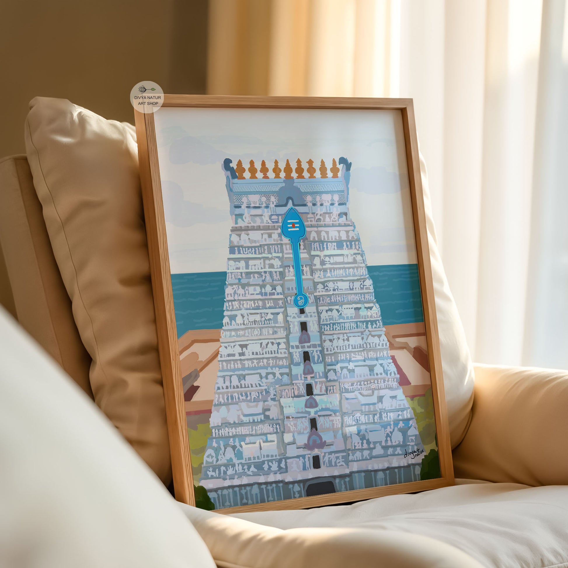 Framed artwork of a Tiruchendur temple tower  on a beige couch.